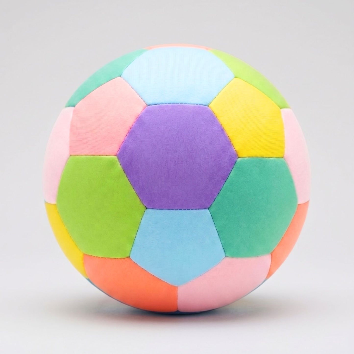 A colorful House Ball - EE made of hexagonal fabric panels in pastel shades of purple, light blue, green, pink, yellow, orange, and teal, centered on a light gray background.