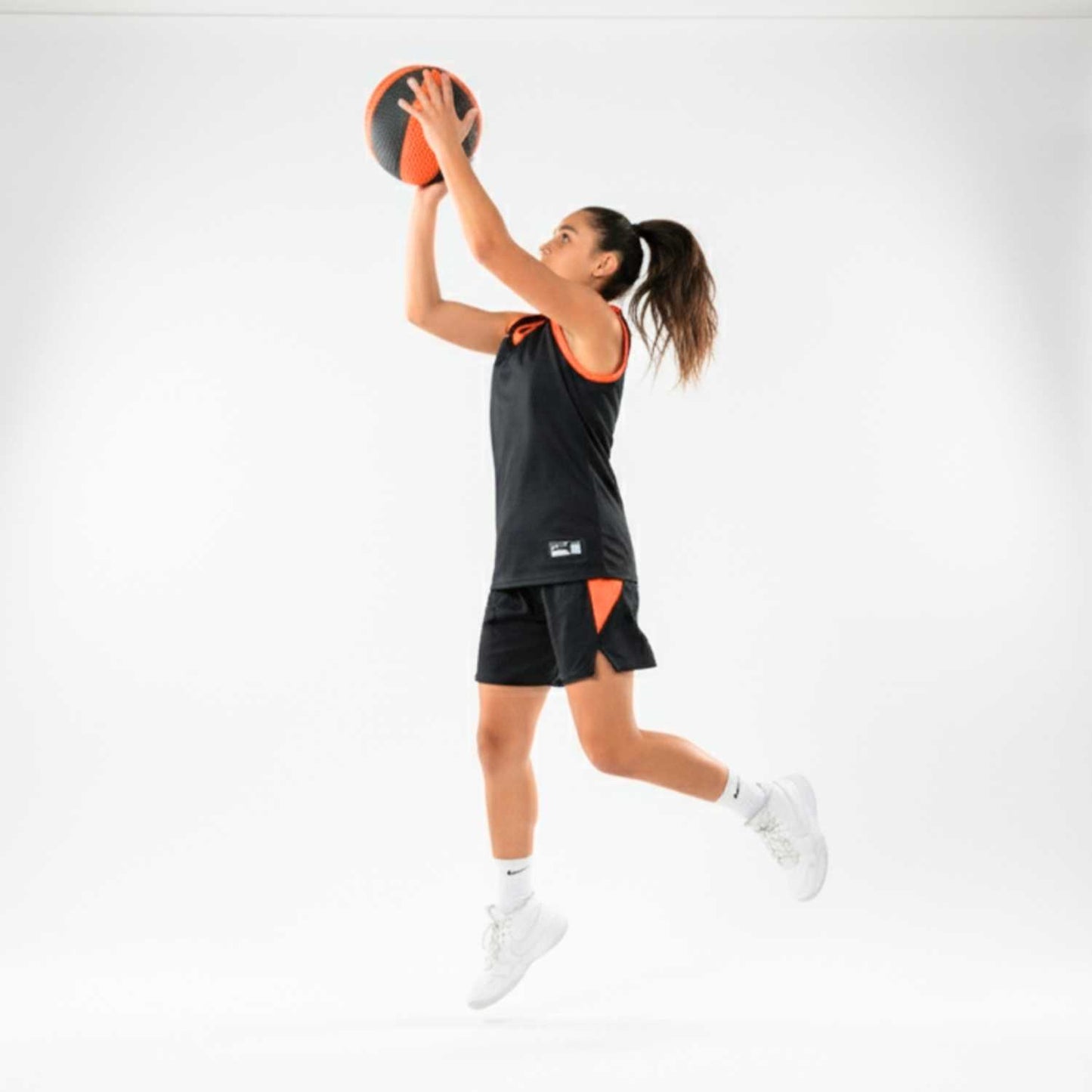Person in athletic wear holding a HouseHoops basketball against a white background