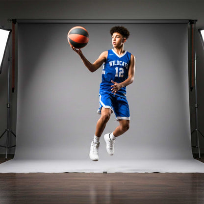 Person in a blue basketball uniform with the number 12 holding a HouseHoops basketball against a gray backdrop.